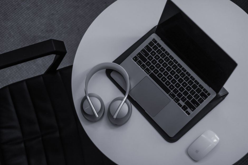 A sleek modern workspace featuring a laptop, headphones, and mouse on a round table.